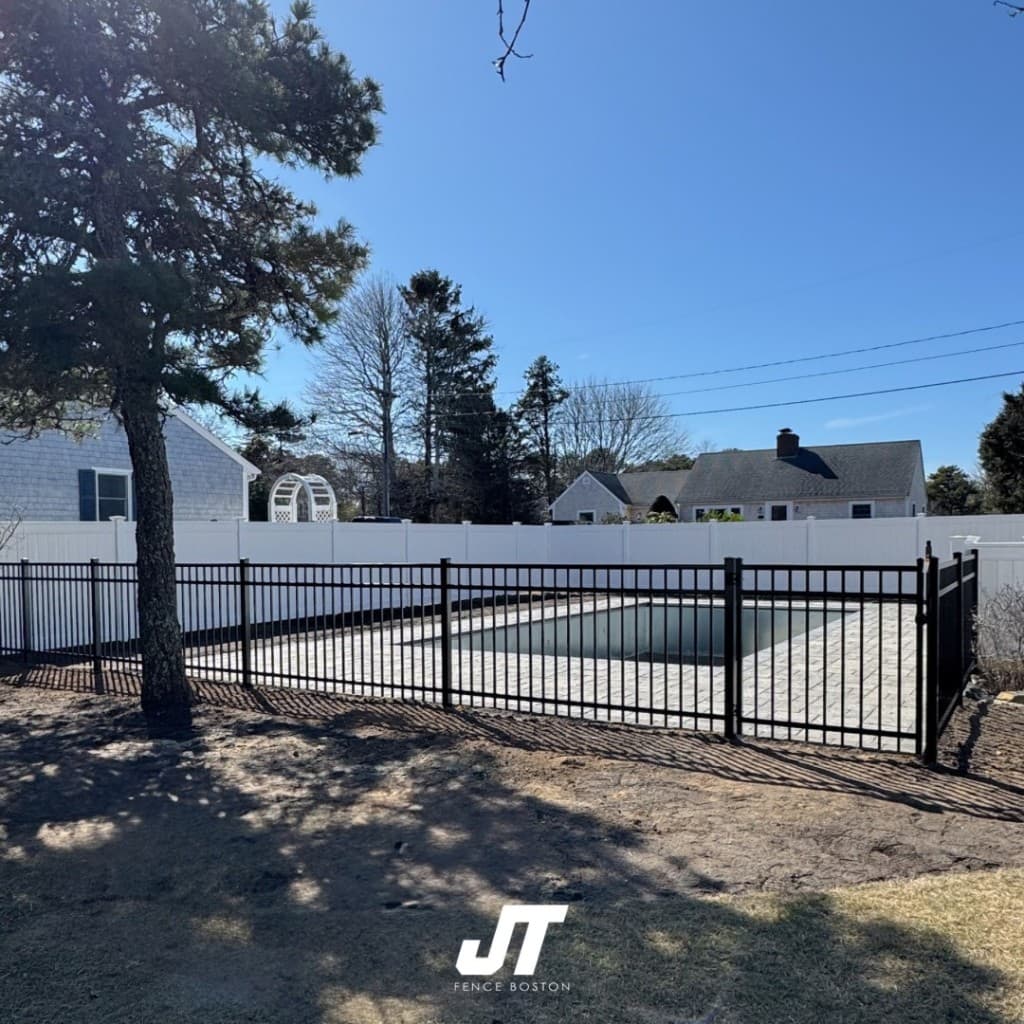 Black ornamental metal pool safety fence with white vinyl privacy perimeter fencing — professional installation by JT Fence Boston