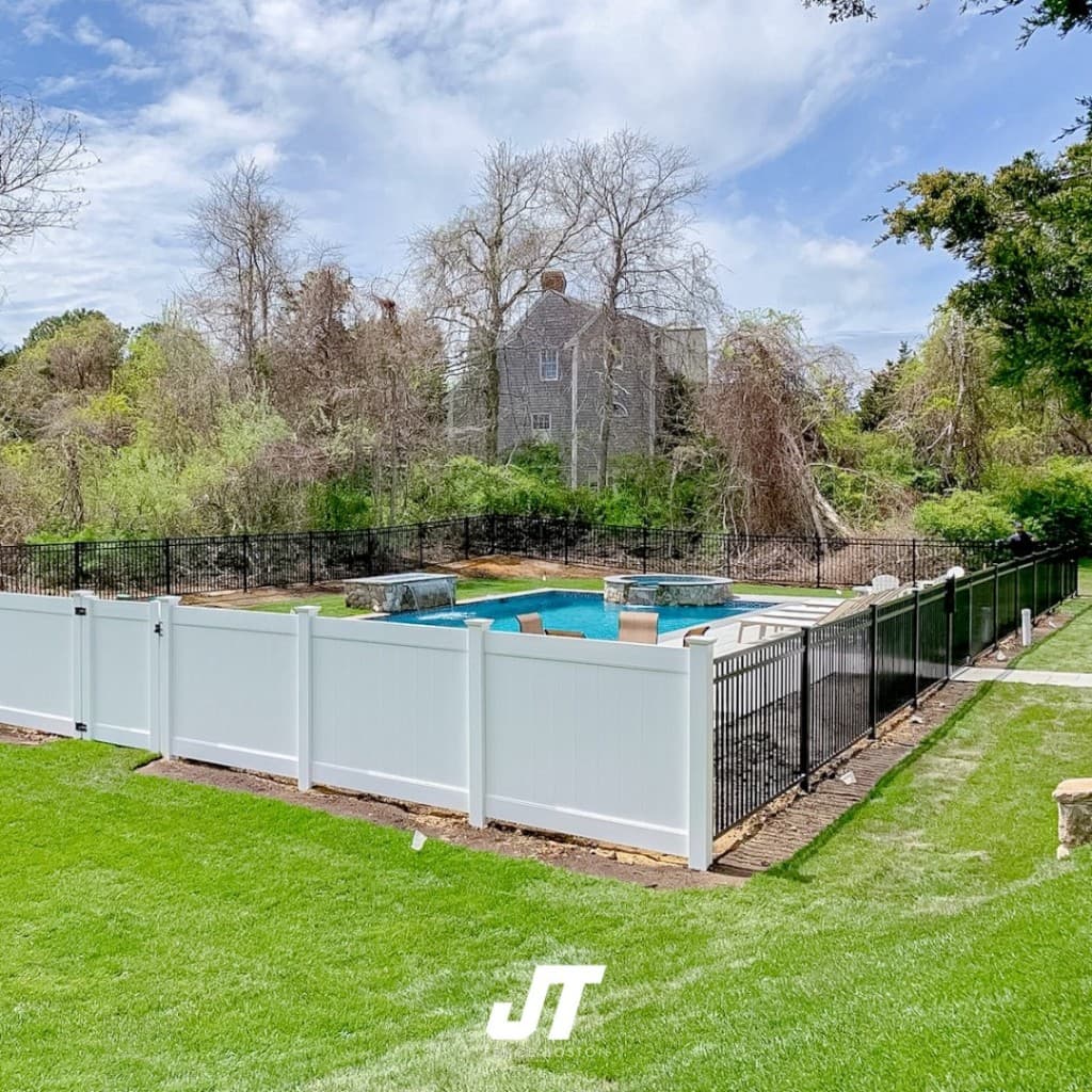 Pool and spa with waterfall, lounge area, and mixed vinyl privacy plus metal pool fence — resort-style backyard